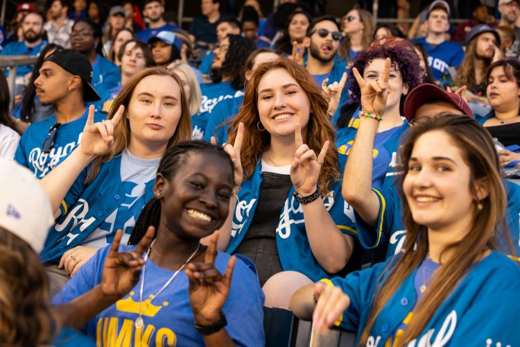 UMKC students wearing UMKC and Royals jerseys, holdingtheir hands in a Roo Up gesture