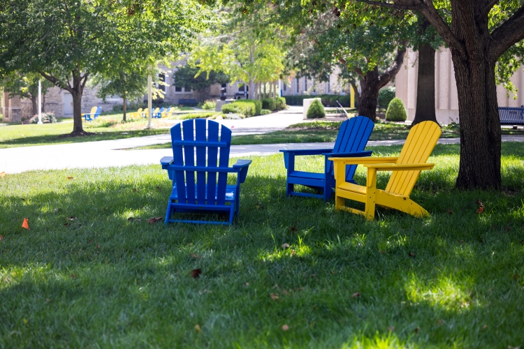 Two blue chairs and one yellow chair on the UMKC quad.