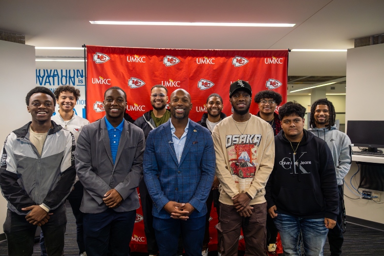 UMKC Men of Color Academy students pose for a group photo with Ramzee Robinson of the Kansas City Chiefs in front of UMKC and Chiefs backdrop