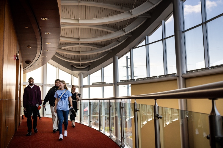 UMKC students walking down the red carpeted hallway on the second floor of the Chiefs training facility by the stairs