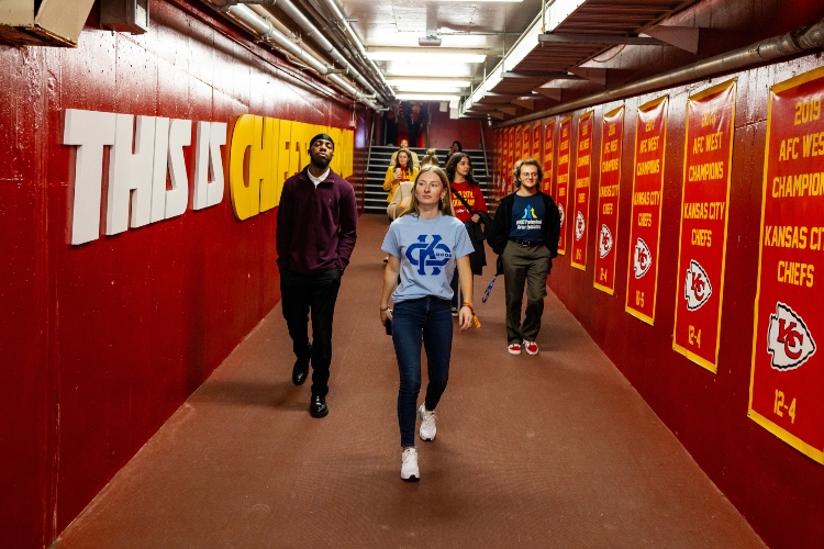 UMKC students at Arrowhead stadium walking through the chiefs branded tunnel that leads them straight on to the field that the chiefs play on
