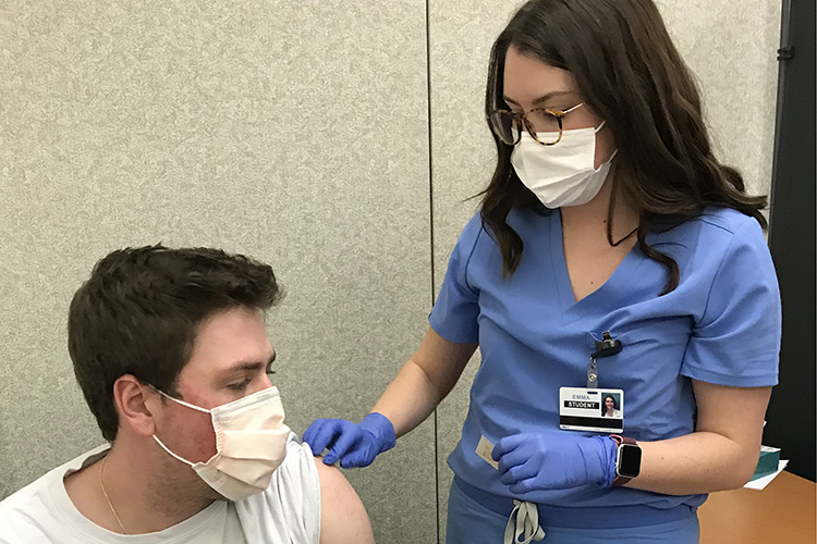 UMKC medical student Emma Smith gives a COVID vaccine to fellow student West Stark. 