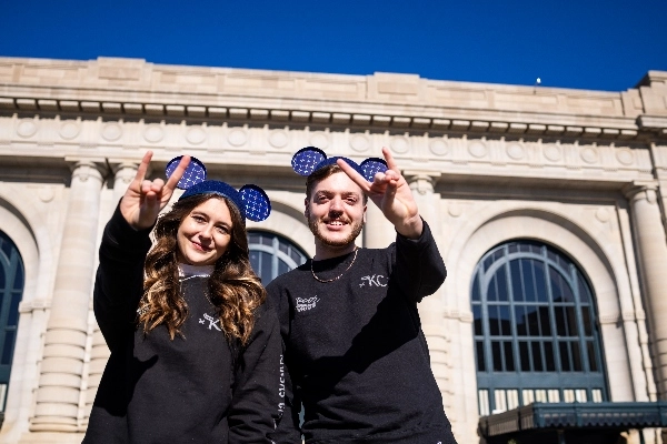 Two people wearing black Roo Mobb shirts hold up the Roo sign and wear Mickey ears