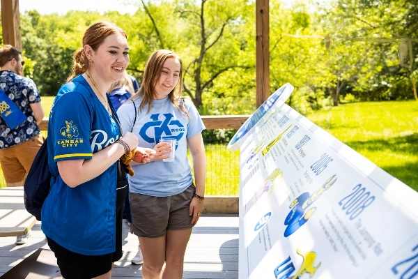 Two people with wearing blue shirts look at the UMKC display at the zoo.