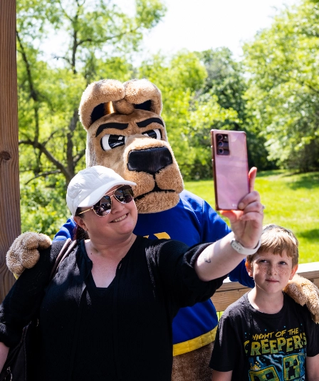 KC roo mascot poses with two zoo visitors during Roo Day at the Zoo.