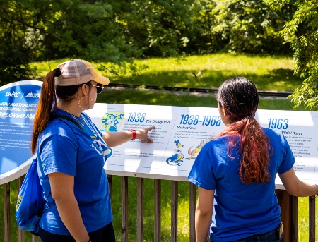 Two zoo visitors look at an infographic installed near the kangaroo exhibit at the Kansas City Zoo.