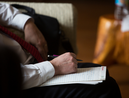 A close up of a council member's hands and notepad as they sit listening to discussion.