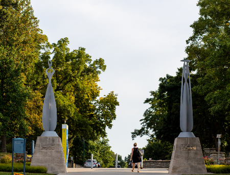 A person walking through the gateway statues on UMKC's campus.