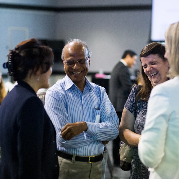 Faculty talking and laughing together at a promotion and tenure event.