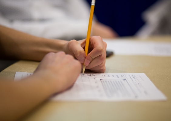 Closeup on a student's hands as they write at their desk.