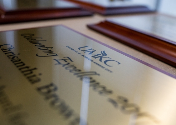 A close-up of a faculty award made of wood and brass laying on a table. 