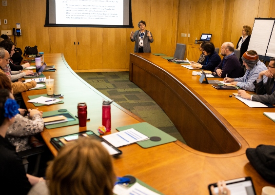 Faculty members and members of the CAFE team talking in a conference room. 