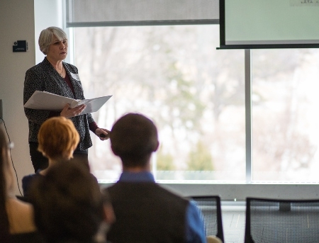 A faculty member giving a lecture at the front of a classroom.