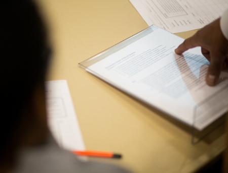 A closeup on an instructors hand pointing at a study sheet laying on a table.