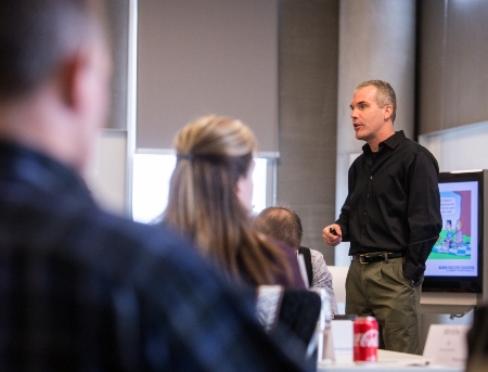 A professor giving a lecture in a modern business classroom.