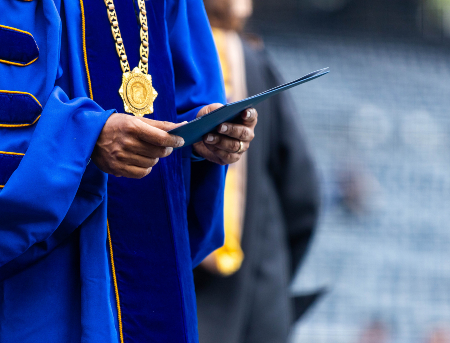 Close up of a professor holding a folder at commencement ceremony.