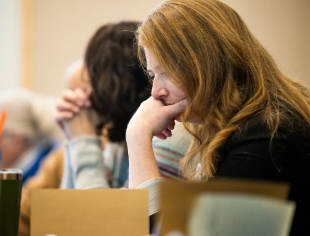A faculty member looking over papers during a council meeting.