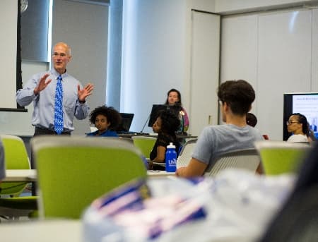 The Bloch School dean, dean Klaas, stands in front of a classroom and gives an animated lecture.