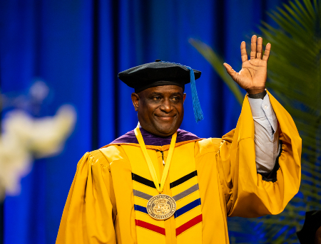 A member of the UM System Board of Curators waves to the crowd during UMKC's commencement ceremony.