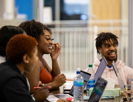 A group of MSA students sitting around a table in the student union talking and smiling while studying.