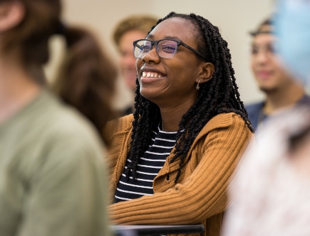 A student smiling while looking towards the front of the class. 