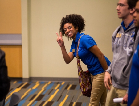 A student smiling and giving the peace sign during new student orientation.