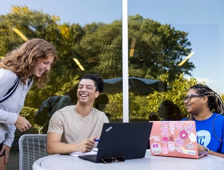 Students sitting at a table outside of the student union laughing and talking together.