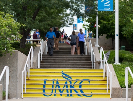Students and faculty walking up and down the main campus staircase, which has the UMKC logo painted on the steps.
