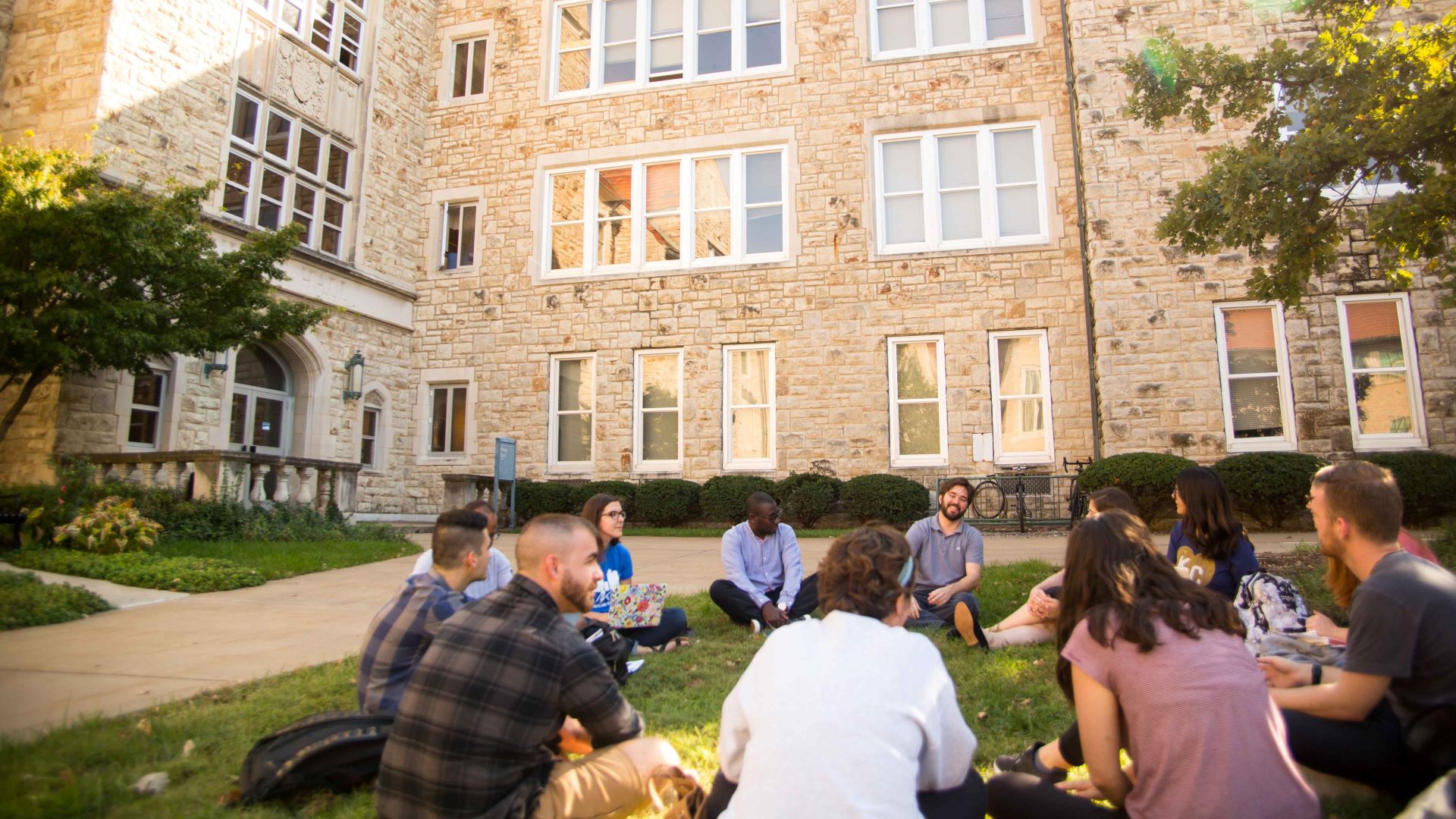 Students sitting in circle on grass on campus