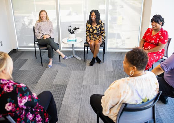 group of people sitting in chairs in circle formation.